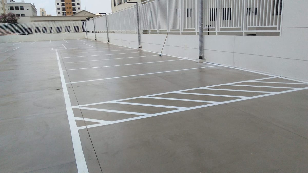 Piso do estacionamento coberto, com faixa de circulação e vagas em sequência