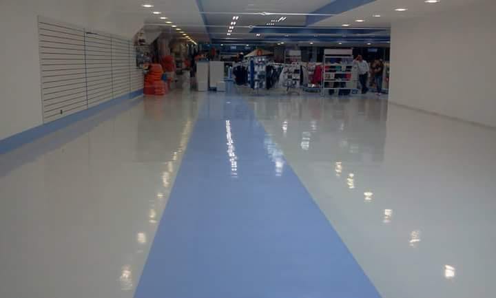 Corredor da galeria com o piso refletindo a iluminação do teto