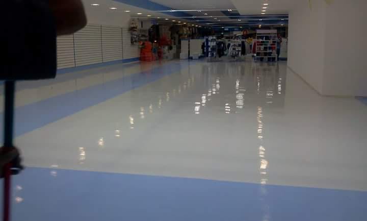 Piso branco de alto brilho com a faixa azul correndo junto às lojas