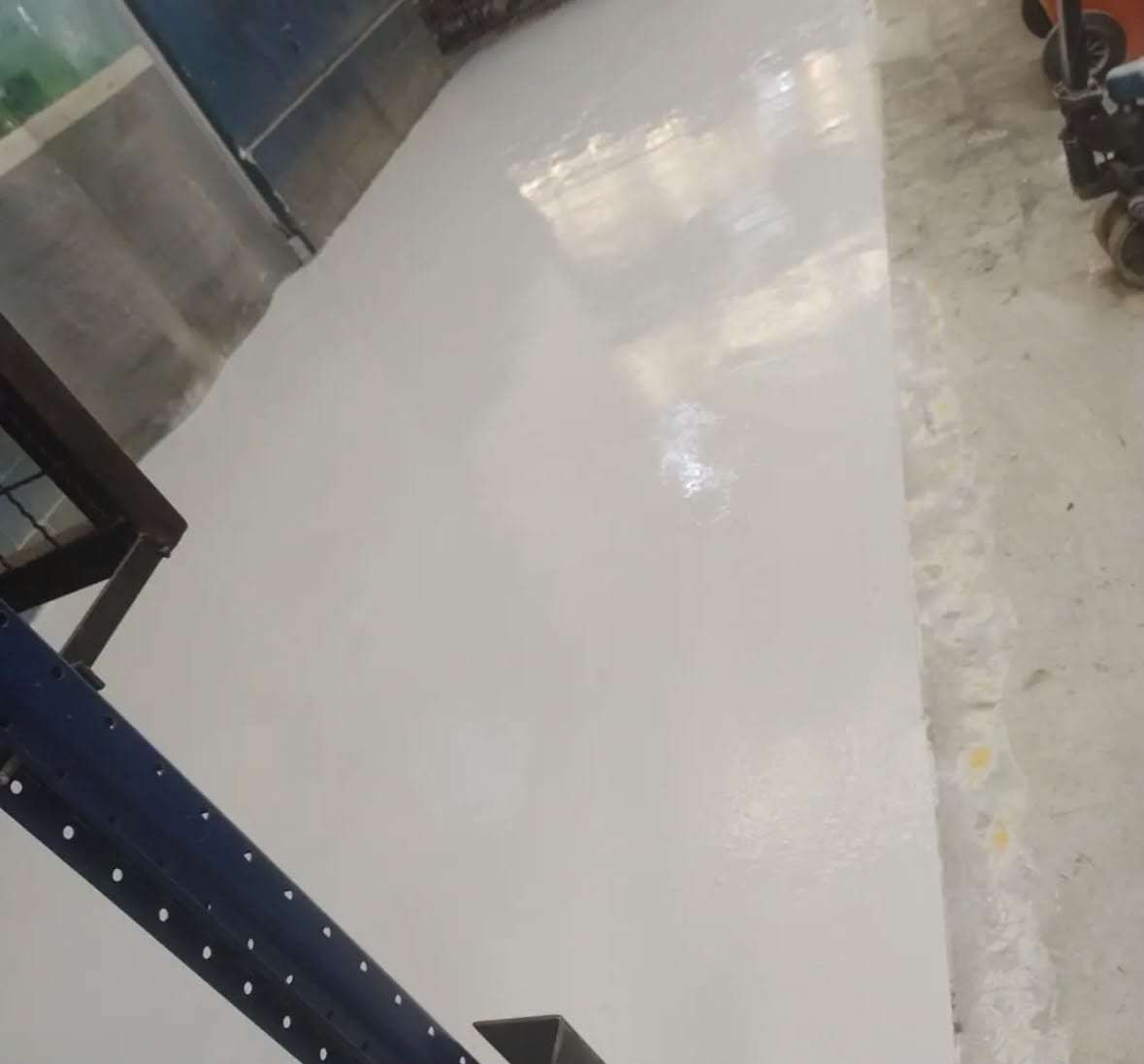 Encontro do piso resinado com a estrutura metálica e o pilar do galpão