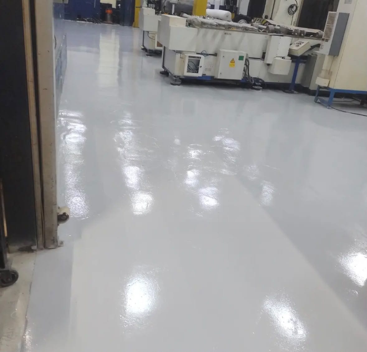 Piso resinado branco de alto brilho em chão de fábrica, entre máquinas operatrizes instaladas