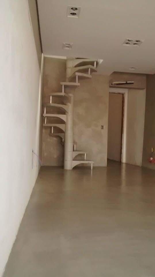Circulação interna com piso contínuo claro e escada caracol ao fundo