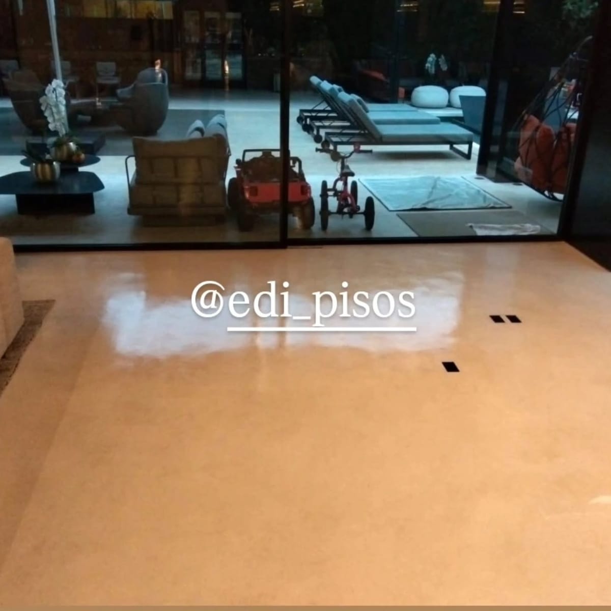 Piso de tecnocimento contínuo em área social de residência, com vista para o deck e a piscina