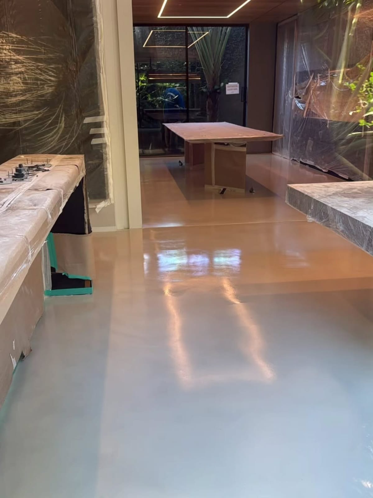 Piso de tecnocimento recém-aplicado em cozinha e sala de jantar, com o mobiliário ainda protegido por plástico